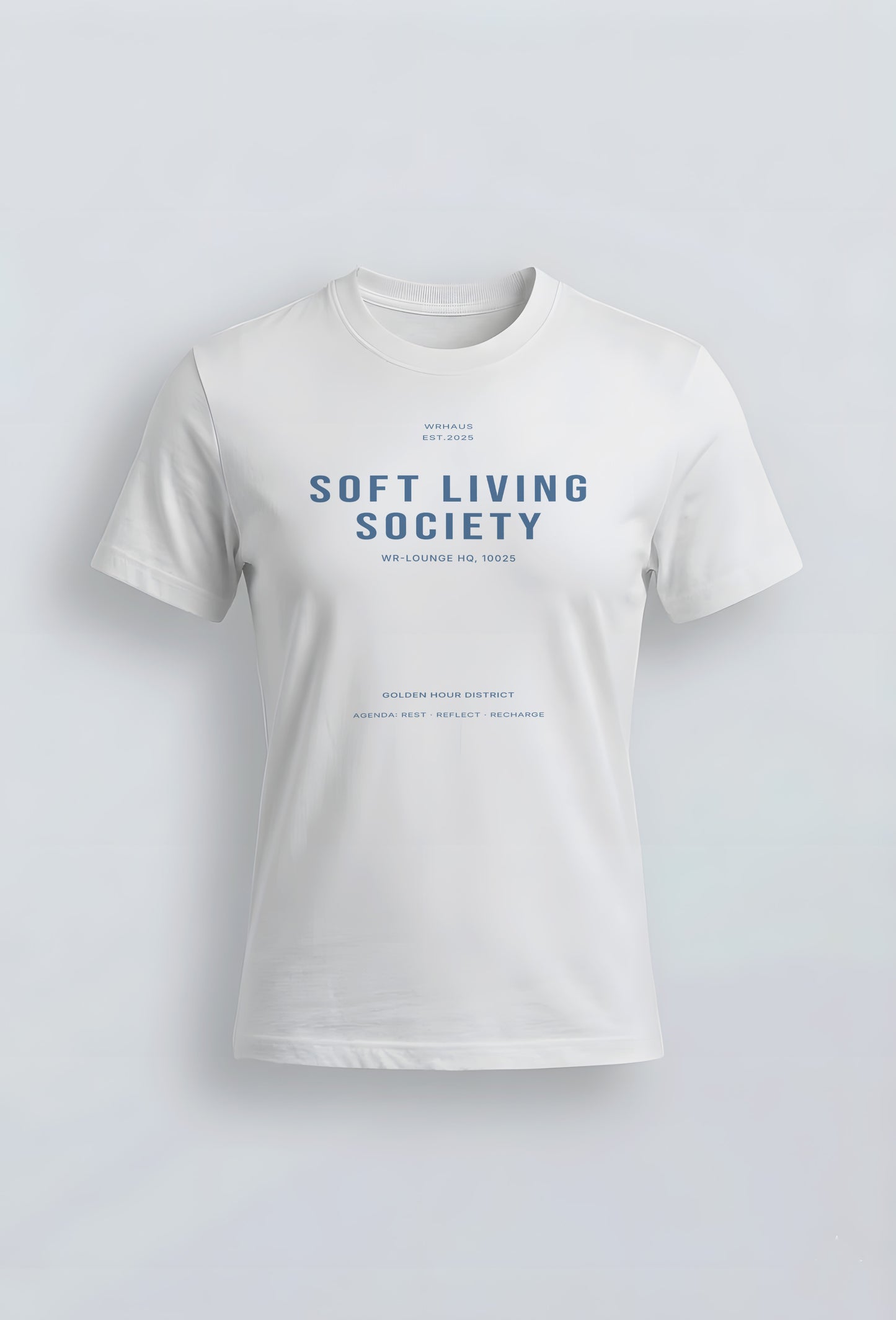 A premium white short-sleeved womens fit t-shirt with a structured fit. The center chest features bold, minimalist typographic design that reads "SOFT LIVING SOCIETY" with smaller archival-style details below it.