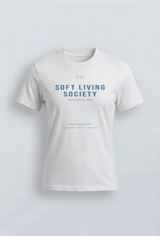 A premium white short-sleeved womens fit t-shirt with a structured fit. The center chest features bold, minimalist typographic design that reads "SOFT LIVING SOCIETY" with smaller archival-style details below it.